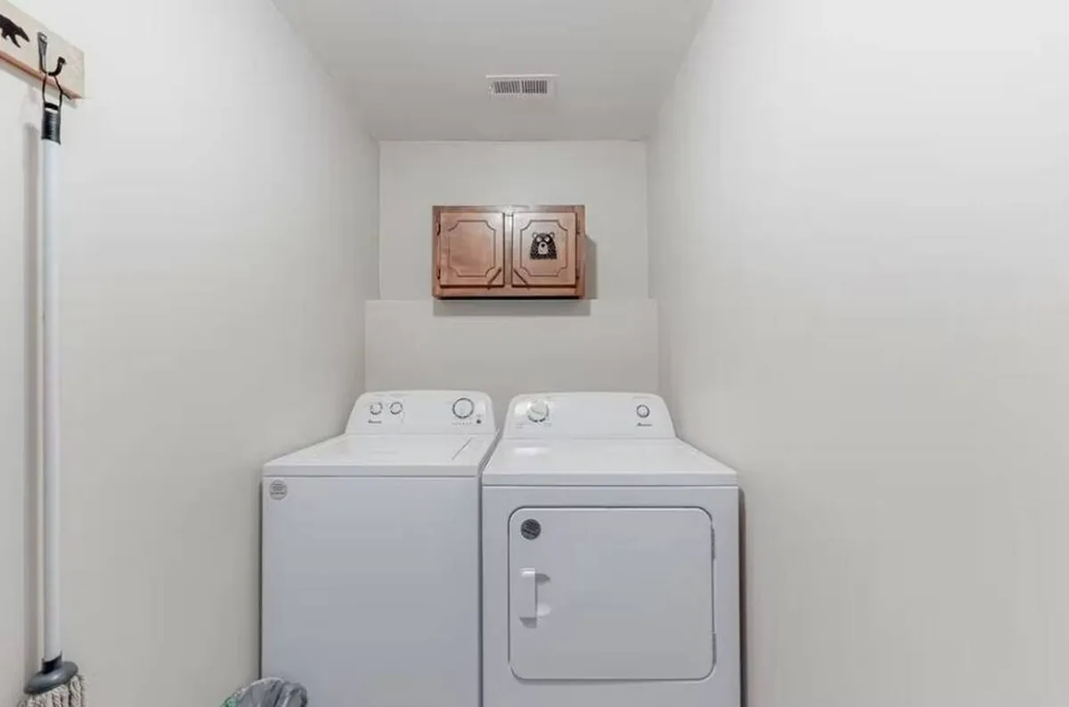 A compact, practical laundry area with a washing machine, dryer, and wooden cabinetry. The setup is neat and accessible, showcasing the convenience available to families staying at Sunflower Haven.
