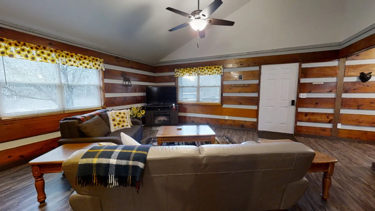 A comfortable living room with a plush sofa, coffee table, large windows, and a television set. The spacious layout encourages relaxing, watching movies, or gathering for an evening chat. Natural light and thoughtful decor create a welcoming mood.